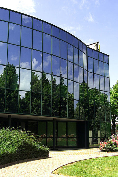 Modern building with glass facade reflecting trees and sky